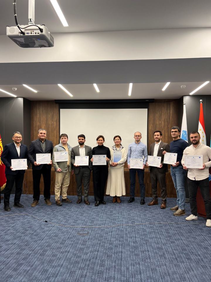 Programme graduates standing in a row holding their certificates