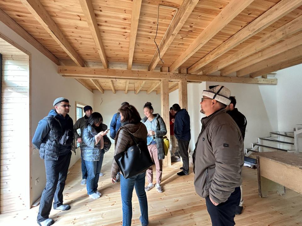 Participants inside the eco-building under exposed timber beams and a timber ceiling