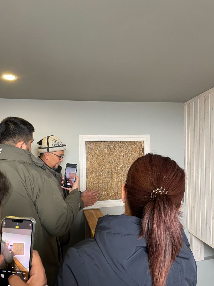 Participants examining an exposed wall panel built with wheat straw